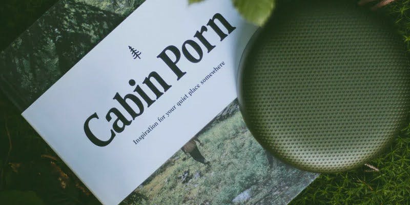 Book titled 'Cabin Porn' on grass, featuring serif fonts and a nature-inspired design.